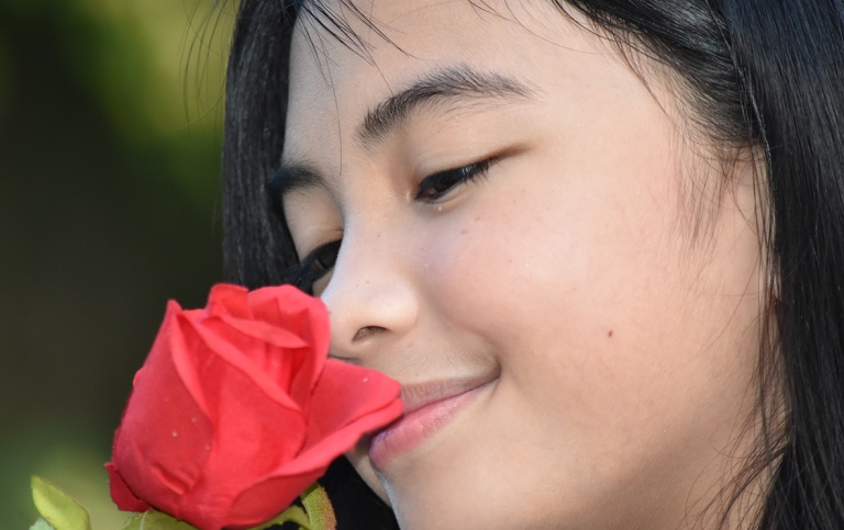 A teen girl smelling a rose