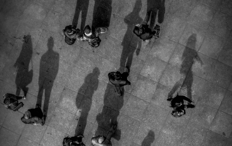 Flygfoto över torg med människor med lång skugga. Foto: Gökhan Sirkeci från Pexels