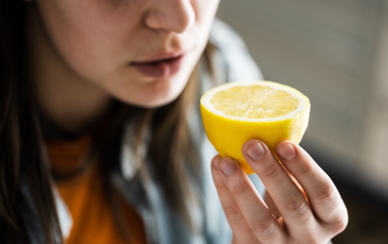 Närbild på en kvinna som luktar på en citronhalva.