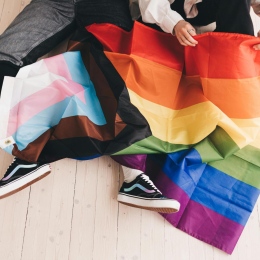 Två personer som vecklar ut en LGBTQIA+ flagga. Foto från Pexels